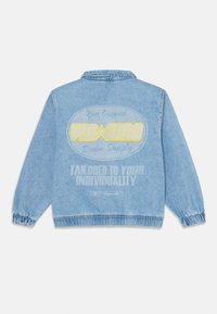 Veste en denim bleu clair avec un col, des poignets élastiques et un imprimé graphique au dos, comprenant du texte et un logo.