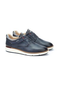 Zapatos de cuero azul marino con un acabado suave, suela de goma blanca, costuras marrones en contraste y acentos rojos en los cordones y los ojales.