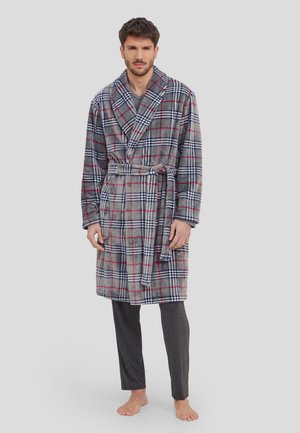 Ropa de casa de cuadros gris con acentos rojos y azules, hecha de tela suave. Presenta un cuello de chal, cinturón en la cintura y mangas largas. Combinada con pantalones oscuros.