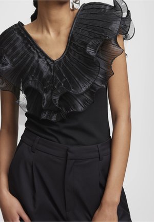 Czarna bluzka z głębokim dekoltem w kształcie litery V oraz eleganckimi plisowanymi falbanami na rękawach. W połączeniu z czarnymi, wysokim stanem spodniami, tworzy wyrafinowaną sylwetkę.