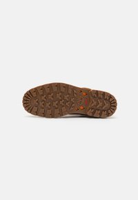 Sola de bota de borracha com sulcos profundos, apresentando um logótipo em relevo e padrões hexagonais. Cor castanha rica com detalhes em laranja.
