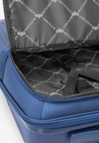Maleta rígida azul con exterior texturizado, abierta para revelar un forro negro con un patrón repetido de logotipos blancos y correas interiores para asegurar los objetos.