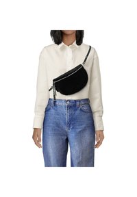 Schwarze Kunstpelz-Crossbody-Tasche mit einem Reißverschluss, getragen über einem weißen Hemd. Verfügt über einen verstellbaren Riemen und eine runde Form. Jeans aus Denim sind darunter sichtbar.