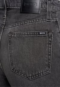 Jeans en denim noir avec une finition texturée, présentant une poche arrière avec une petite étiquette "BIG STAR" et une étiquette en cuir à la taille.