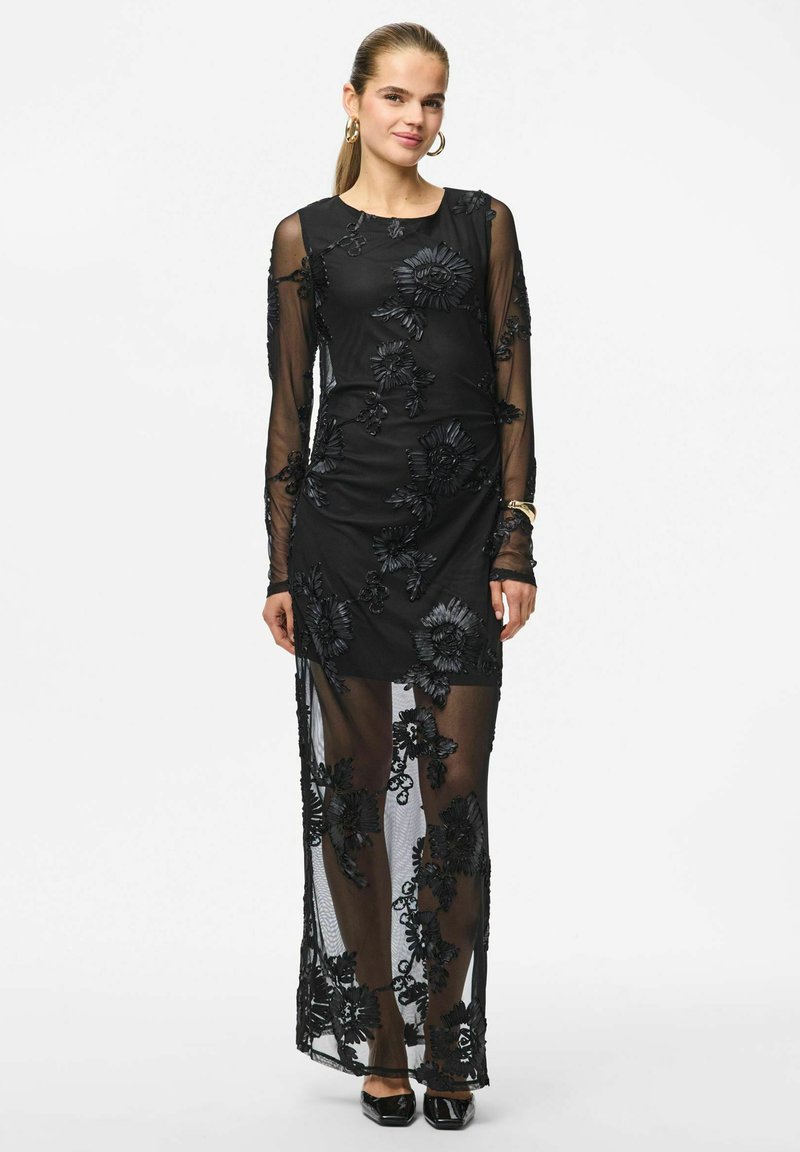 Must kleit, millel on pikad läbipaistvad varrukad, lillemustriga tikand ja reie kõrgune lõhik. Põhiriie on ühtlane, lillemustriga tekstureeritud.