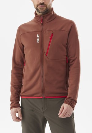 Veste en polaire marron avec un col montant, fermeture éclair rouge et accents, dotée d'une poche poitrine et de poches latérales. Texture lisse et design ajusté.