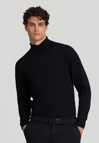 Maglione a collo alto di colore nero realizzato in un tessuto morbido con maniche lunghe. Presenta un design aderente e una texture liscia e minimale, priva di motivi.