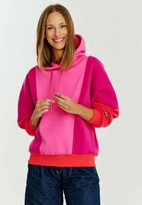 Mikina s kapucí v růžových a korálových barevných blocích, s tkaničkou a žebrovanými manžetami, vyrobená z měkké, strukturované látky.