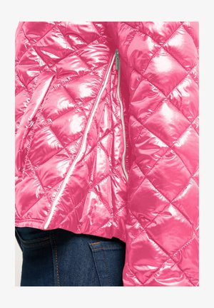 Glanzend roze doorgestikte jas met diagonale diamantstiksels en een verticale zilveren ritssluiting, gedragen over donkerblauwe spijkerbroek.