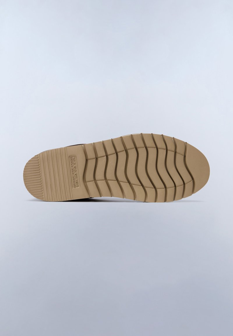 Suola di sneaker in gomma marrone con scanalature testurizzate, caratterizzata da una punta arrotondata e righe distintive per la trazione. Nessun logo visibile o dettagli aggiuntivi.