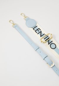 Sangle en faux cuir bleu clair avec des accessoires en métal doré. Comprend une section en tissu avec "VALENTINO" en lettres noires en gras.