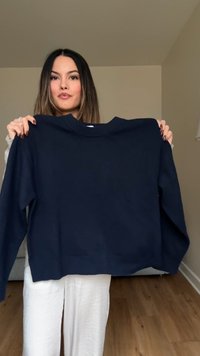 Dunkelblauer, kurzer Pullover mit geripptem Rundhalsausschnitt und langen Ärmeln, aus strukturiertem Material. Keine sichtbaren Muster oder Akzente.