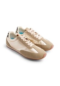 Zapatos deportivos beige con una mezcla de materiales suaves y texturizados, con cordones en la parte delantera, acentos en contraste y suela de goma.
