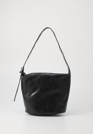 Schwarze Leder-Bucket-Bag mit einem einzelnen Schulterriemen und einem Reißverschluss oben vor einem schlichten hellen Hintergrund.