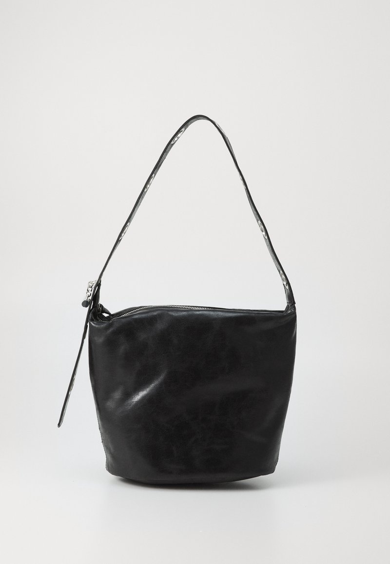 Sac seau en cuir noir avec une seule bandoulière et une fermeture éclair sur le dessus, sur un fond clair uni.