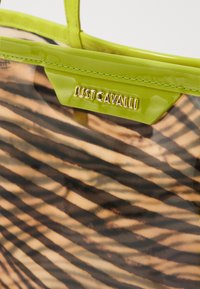 Borsa a tracolla traslucida con un motivo a righe nei toni del marrone e del nero, dotata di vivaci manici verdi e di una placca logata metallica.