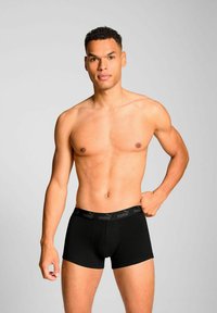 Black boxer briefs made of soft fabric, featuring a snug fit and a logo-emblazoned waistband, displayed on a torso against a plain background.