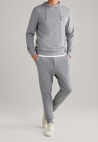 Sudadera gris con capucha y bolsillo tipo canguro, combinada con pantalones ajustados a juego. Presenta un cordón blanco, un logo sutil y puños acanalados.