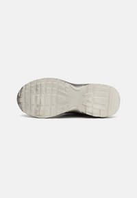 Shoe sole with a rugged design, made of grey rubber. Features a textured tread pattern for traction, rounded shape, and smooth edges.
