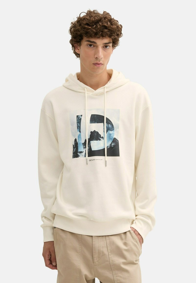 Sudadera color crema con un gráfico rectangular que presenta montañas y nubes. Incluye cordones y puños y dobladillo acanalados.