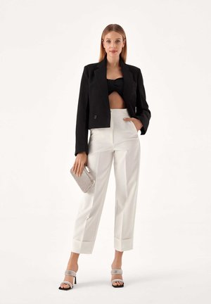 Sacou negru scurt, top bandeau negru, pantaloni albi cu talie înaltă și mansete, sandale cu toc bloc argintii și un clutch argintiu.