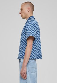 Camicetta a maniche corte a quadri blu con colletto, realizzata in tessuto intrecciato, con una vestibilità rilassata e orlo dritto.