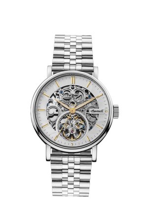 Montre en acier inoxydable argenté avec un cadran squelettique, des motifs complexes, des accents dorés et bleus, et un bracelet texturé en argent.
