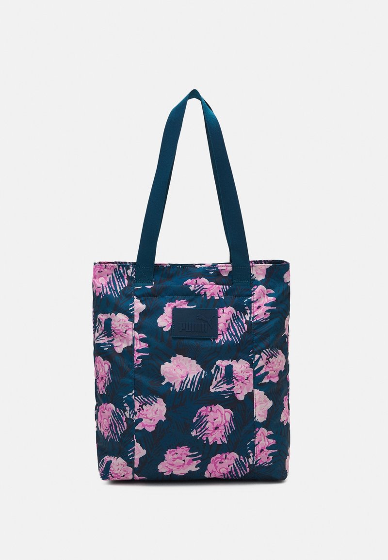 Sac fourre-tout en toile à imprimé floral bleu marine avec motifs de fleurs roses et violettes, doté de bretelles bleues et d'une étiquette de marque texturée.