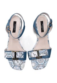 Sandales en cuir bleu avec une semelle intérieure à motif présentant des designs géométriques, des accents en métal doré et une large lanière sur le devant du pied.