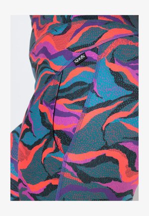 Obcisłe legginsy z żywymi falistymi wzorami w kolorach morskim, fioletowym, pomarańczowym, czarnym i różowym, z małą czarną metką z białym napisem "SPIRITS".