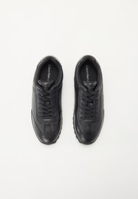 Black leather sneakers with a low profile, round toe, textured accents, and flat laces. Features a subtle logo on the tongue.