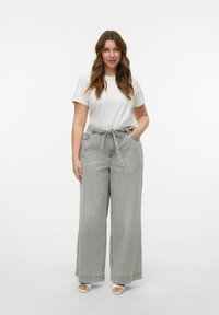 Jeans grises de pierna ancha con cintura ajustable, combinados con una camiseta blanca. La tela tiene una textura ligera, enfatizando un estilo casual.