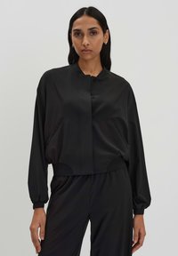 Schwarze, cropped Jacke mit Knopfverschluss, Seitentaschen und oversized Ärmeln. Glatte Textur und minimalistisches Design.