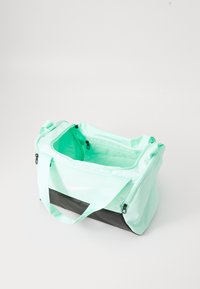 Bolsa de deporte de nailon verde menta con fondo negro, aberturas de cremallera dual y correas ajustables. Presenta el logo de Nike en el lateral.