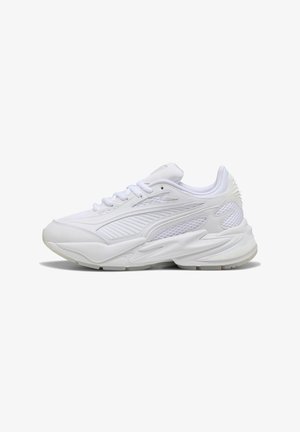 Sneakers de sport blancs avec des superpositions en maille et en synthétique, semelle épaisse et rembourrée, ainsi que des détails texturés au niveau du talon, présentés en profil gauche.