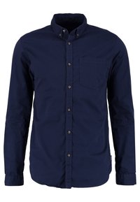 Tummansininen pitkähihaisten paita, joka on valmistettu puuvillasta. Paidassa on nappikaulus, etutasku ja ruskeat napit, joissa on erottuva ommel.