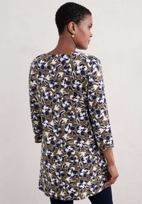 Kwiatowa tunika z zieloną bazą w białe i granatowe kwiaty. Posiada rękawy o długości 3/4 i okrągły dekolt, wykonana jest z miękkiego materiału.