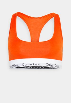 Oranžinė medvilninė sportinė liemenėlė su apvaliu iškirpimu ir lenktos nugaros dizainu. Yra balta juosta su juodu "Calvin Klein" logotipu.