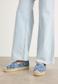 Blauwe canvas espadrilles met gemusterd stof, strooien zolen en blauwe accenten. Draagt in combinatie met lichtblauwe brede spijkerbroek.