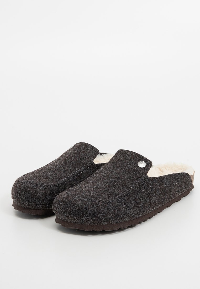 Donkergrijze vilten slippers met een zachte crème voering, open achterkant ontwerp, ronde neus en een zilveren knopaccent aan de buitenzijde.