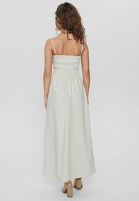 Weißes Maxikleid mit gerafftem Oberteil, leichtem Stoff, verstellbaren Spaghettiträgern und einem ausgestellten Rock, das sich durch ein minimalistisches Design auszeichnet.