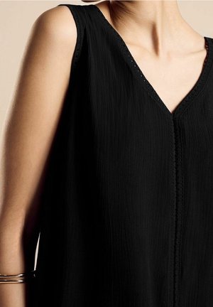 Czarny bezrękawnik z dekoltem w kształcie litery V, o fakturowanej tkaninie i koronkowych detalach na dekolcie, z prostym wykończeniem dolnym i luźnym krojem.