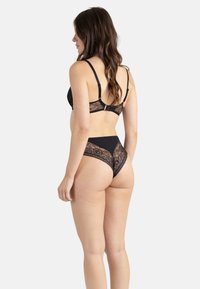 Soutien-gorge en dentelle noire et string assorti, présentant des panneaux en dentelle transparente, des motifs floraux et une ceinture noire unie, conçus pour un confort doux.