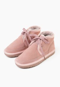 Stivaletti alla caviglia in suede rosa con rivestimento in pelliccia, punta rotonda e lacci abbinati. Presentano occhielli dorati e suola in gomma per una migliore aderenza.