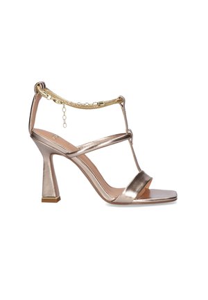 Sandalia de tacón alto en rosa dorado metálico con tiras finas y detalle de pulsera de tobillo con cadena dorada, con puntera cuadrada y tacón acampanado.