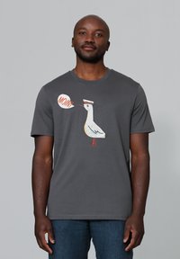 Graues T-Shirt mit kurzen Ärmeln, das ein Karikatur-Möwenmotiv mit der Sprechblase "MOIN!" in Orange und Weiß zeigt. Aus weichem Baumwollmaterial.