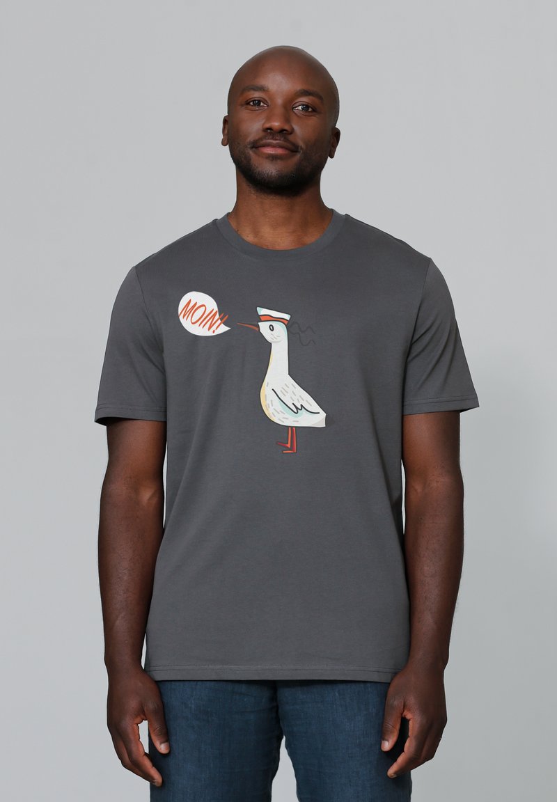 Graues T-Shirt mit kurzen Ärmeln, das ein Karikatur-Möwenmotiv mit der Sprechblase "MOIN!" in Orange und Weiß zeigt. Aus weichem Baumwollmaterial.