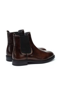 Botas Chelsea de cuero marrón con paneles laterales elásticos, un diseño elegante y un acabado texturizado. Suela de goma negra y detalles de costura sutiles.