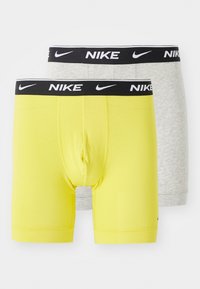 Dve sady boxeriek Nike: jedny v jasne žltej bavne s čiernym pásom a jedny v šedej bavne s čiernym pásom.