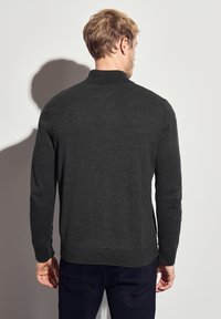 Tmavě šedý pletený svetr s vysokým límcem, dlouhými rukávy a hladkou texturou. Zadní strana ukazuje jednoduchý design bez vzorů.